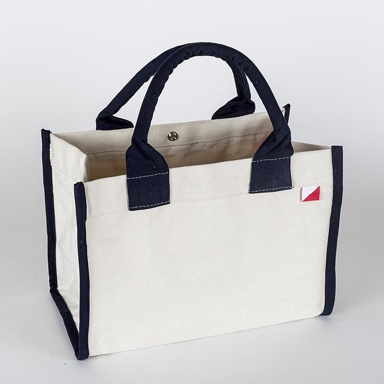 Village Tote Bag with rolled canvas handles and structured design, featuring three interior pockets for organization.
