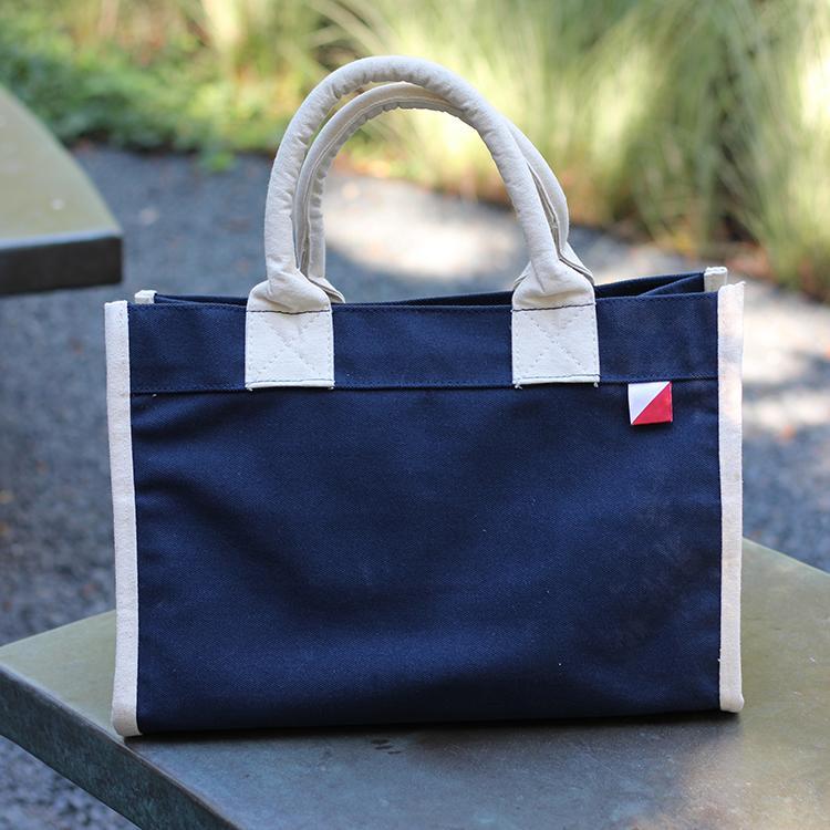 Village Tote Bag with rolled canvas handles and structured design, featuring three interior pockets for organization.