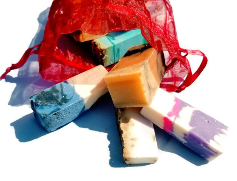A vibrant jewel-toned bag filled with assorted handmade soap samples, showcasing various colors and textures.