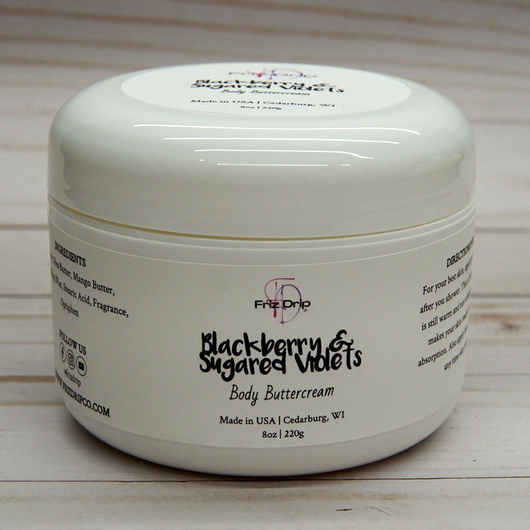 A jar of Blackberry & Sugared Violets Body Cream showcasing its creamy texture and vibrant label, surrounded by blackberries and violets.