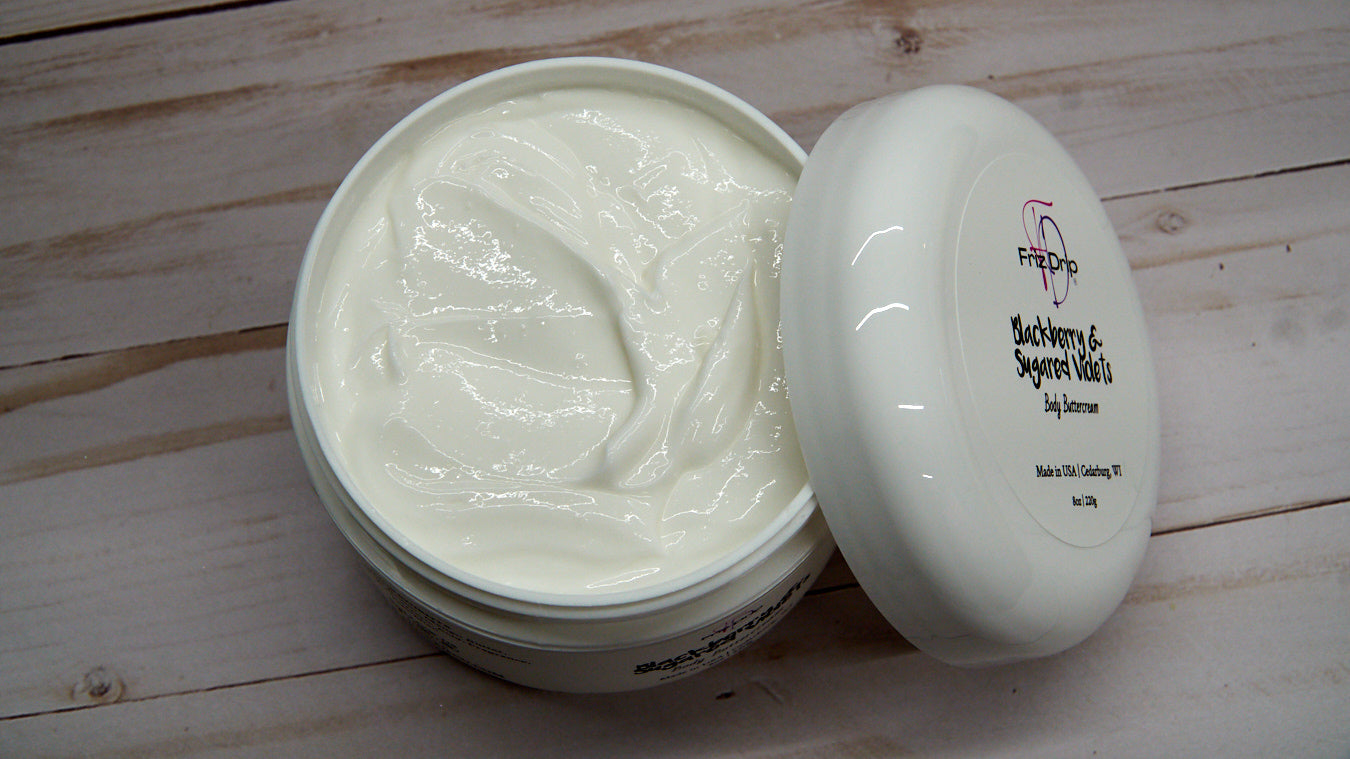 A jar of Blackberry & Sugared Violets Body Cream showcasing its creamy texture and vibrant label, surrounded by blackberries and violets.