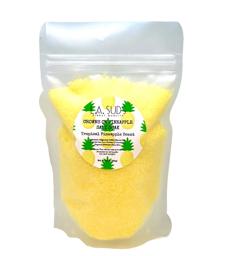 A vibrant package of Crowns On Pineapple Salt Soak featuring tropical pineapple design, showcasing its soothing and skin-benefiting properties.