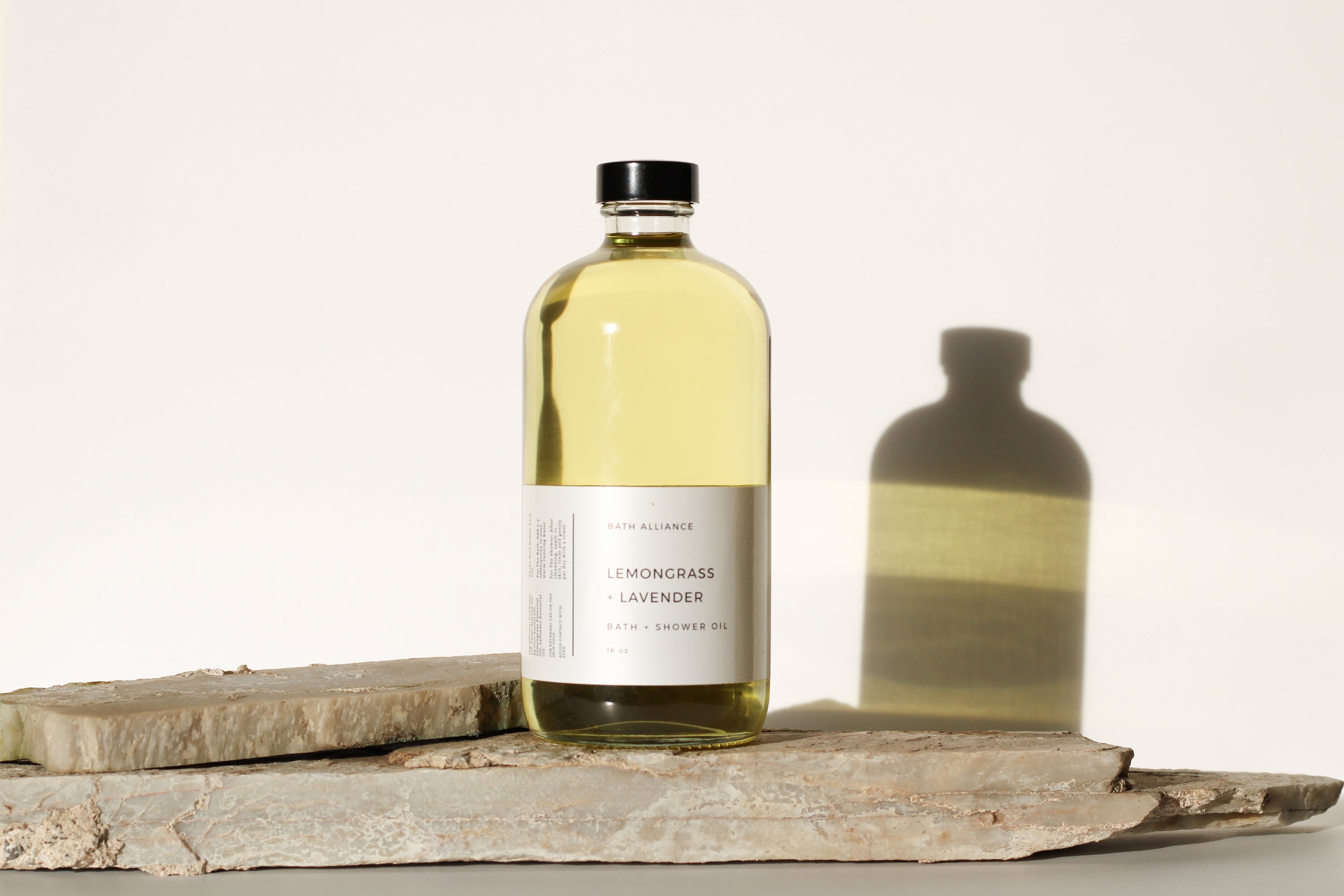 A 6 oz jar of Lemongrass + Lavender Bath + Shower Oil, showcasing its vibrant color and natural ingredients.