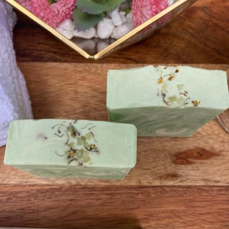 Lemongrass soap bar with essential oils, showcasing its creamy texture and vibrant color, placed on a natural wooden surface.