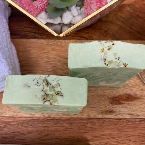 Lemongrass soap bar with essential oils, showcasing its creamy texture and vibrant color, placed on a natural wooden surface.