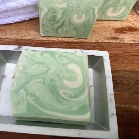 Lemongrass soap bar with essential oils, showcasing its creamy texture and vibrant color, placed on a natural wooden surface.