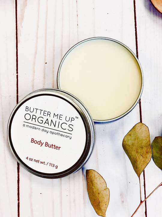 A jar of Organic Body Butter with a creamy texture, surrounded by natural ingredients like shea butter, cocoa butter, and avocado oil, showcasing its moisturizing properties.