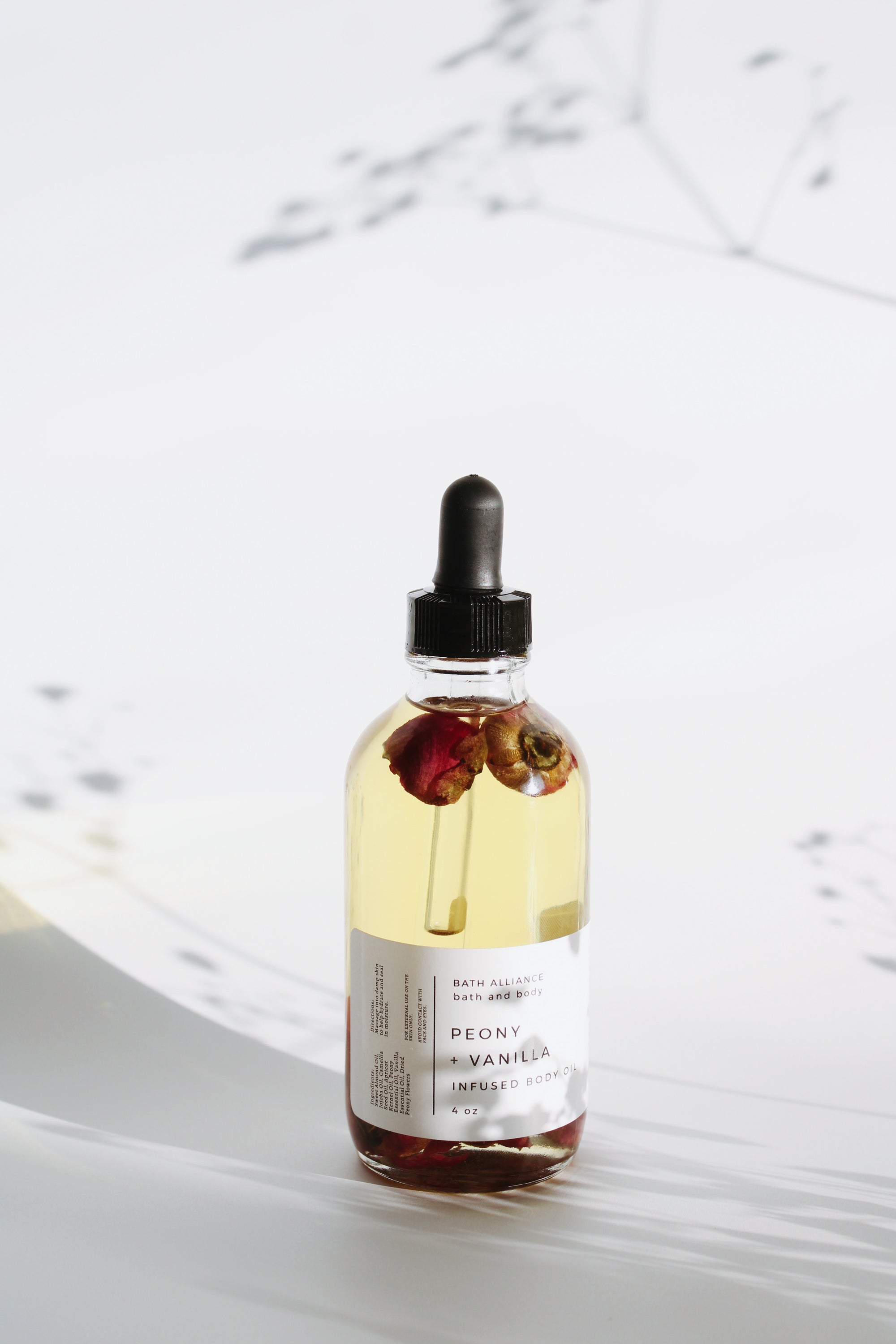 A bottle of Peony + Vanilla Body Oil with a floral design, showcasing its luxurious texture and natural ingredients.
