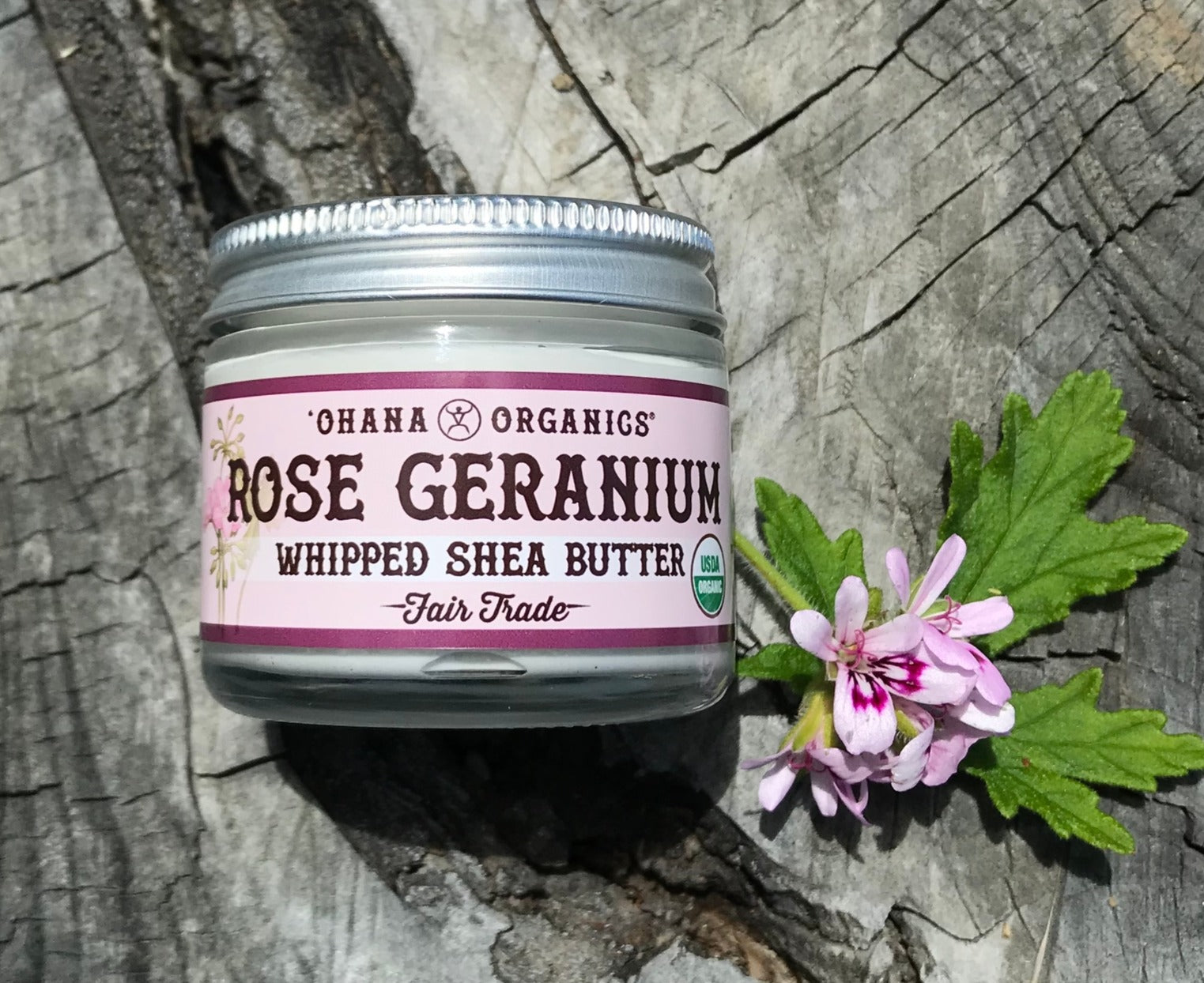 A 2oz glass jar of Rose Geranium Whipped Shea Butter with a creamy texture, surrounded by rose petals.