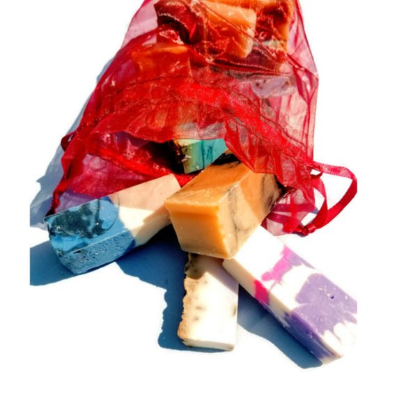 A vibrant assortment of handmade vegan soaps in jewel tones, showcasing various shapes and sizes in a decorative bag.