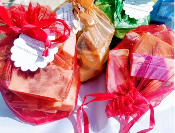 A vibrant assortment of handmade vegan soaps in jewel tones, showcasing various shapes and sizes in a decorative bag.