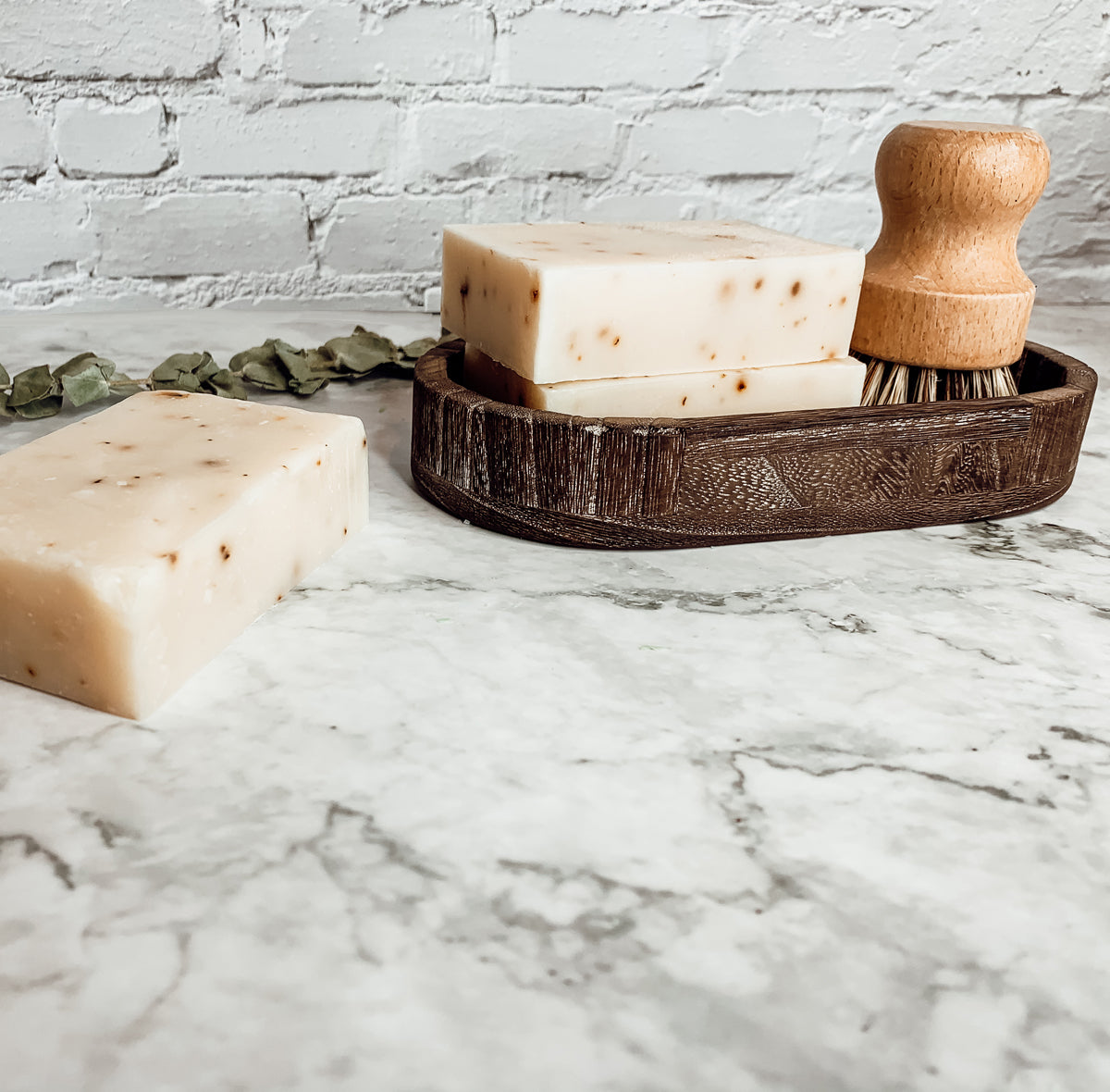A bar of Tea Tree Mint soap featuring a blend of tea tree oil and peppermint leaves, showcasing its natural colors and texture.