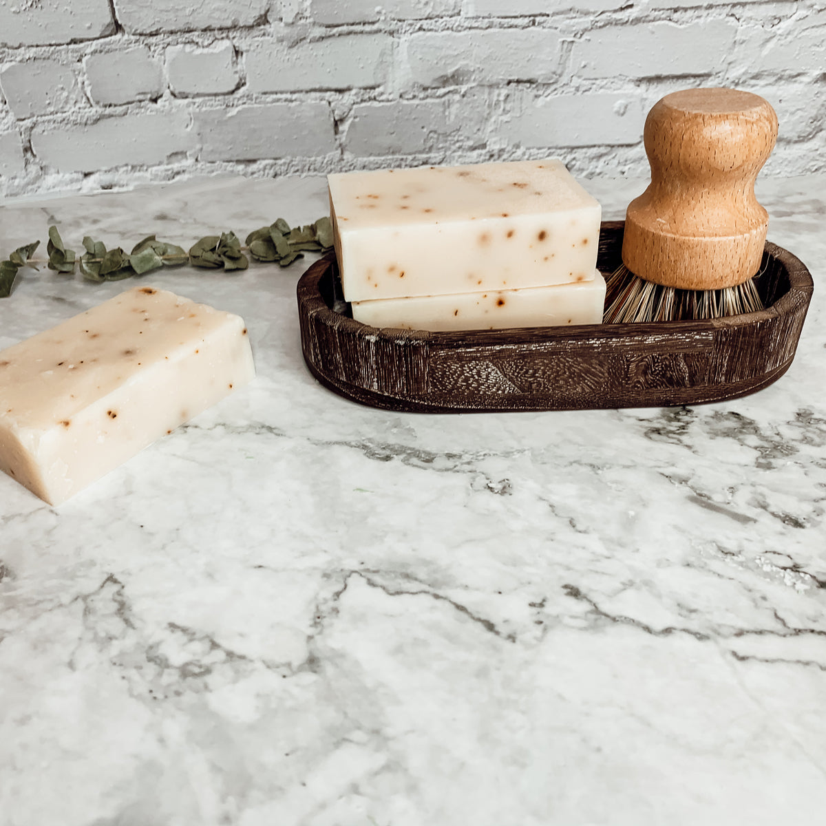 A bar of Tea Tree Mint soap featuring a blend of tea tree oil and peppermint leaves, showcasing its natural colors and texture.