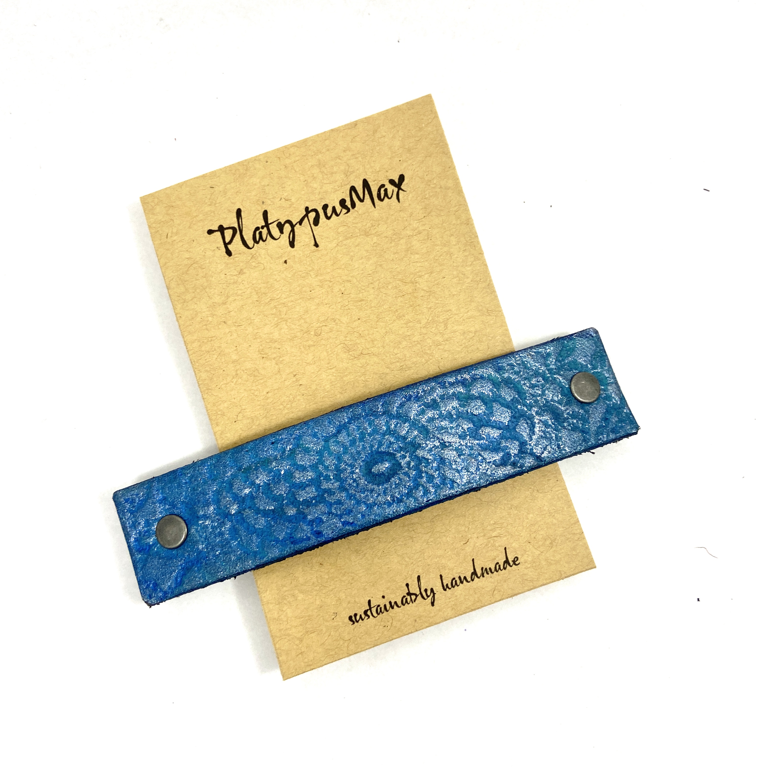 Brilliant blue and turquoise leather hair barrette with mandala imprint, showcasing rustic texture and eco-friendly design.