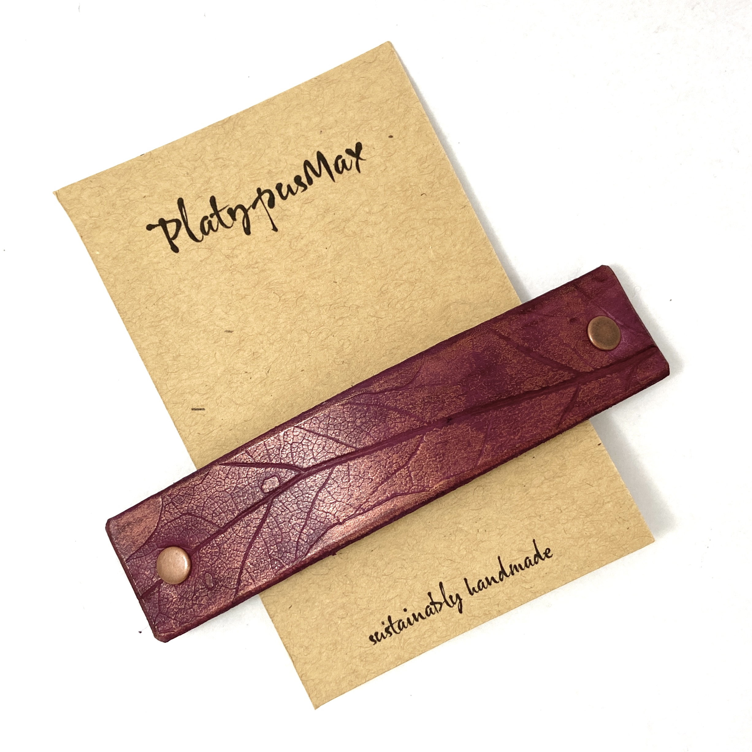 Purple and copper leather hair barrette with oak leaf imprint, showcasing rich colors and unique texture.