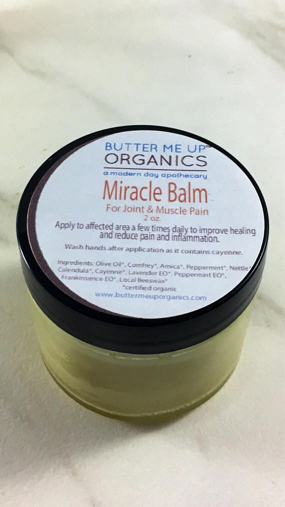 Organic Herbal Pain Balm in a small jar, showcasing its natural ingredients like arnica and peppermint, designed for muscle and joint pain relief.