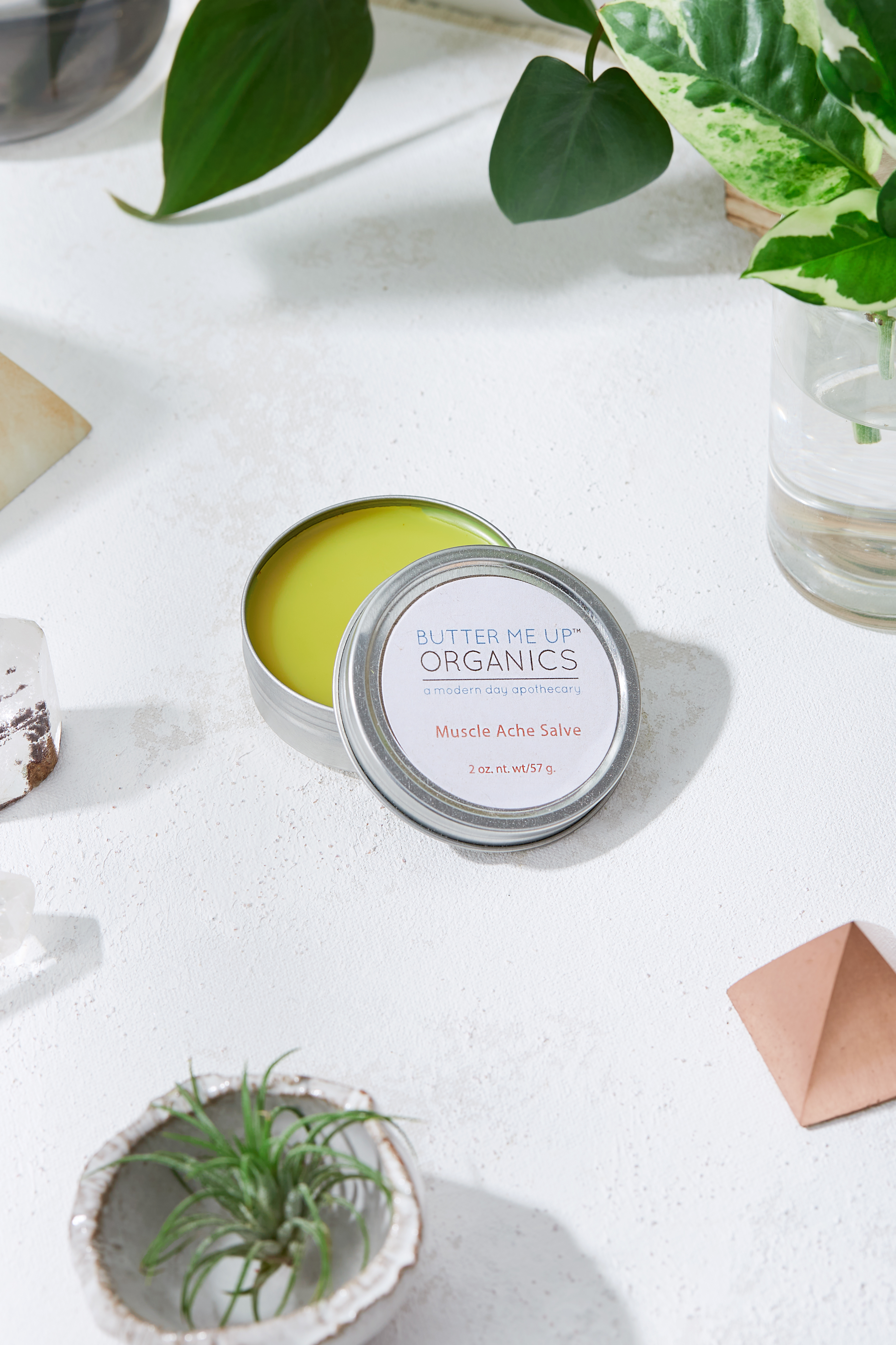 Organic Muscle Ache Salve in a 2oz container, featuring a reddish balm infused with cayenne pepper and other natural ingredients for muscle relief.