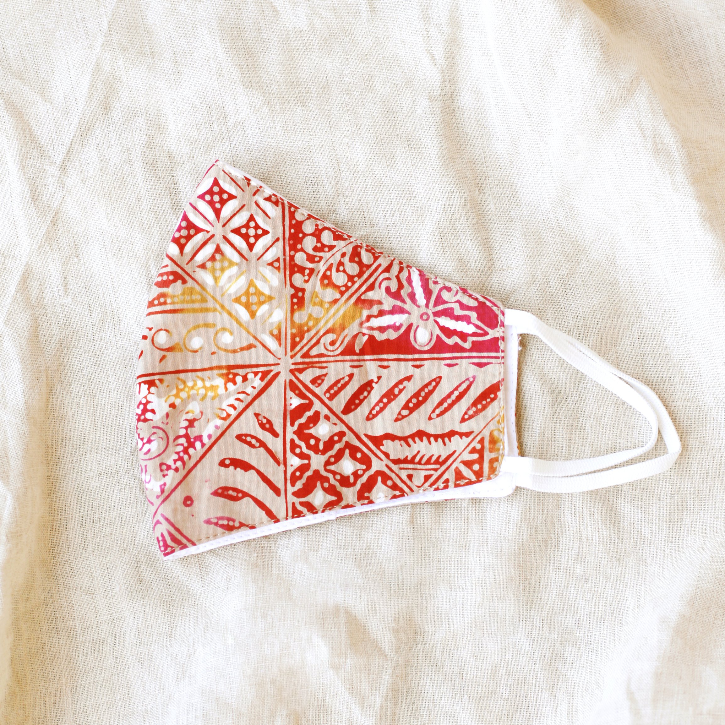 A vibrant RED JAVA Triple Layer Vintage Batik Face Mask featuring intricate patterns, made from traditional hand-stamped Batik fabric, with a waterproof filter included.