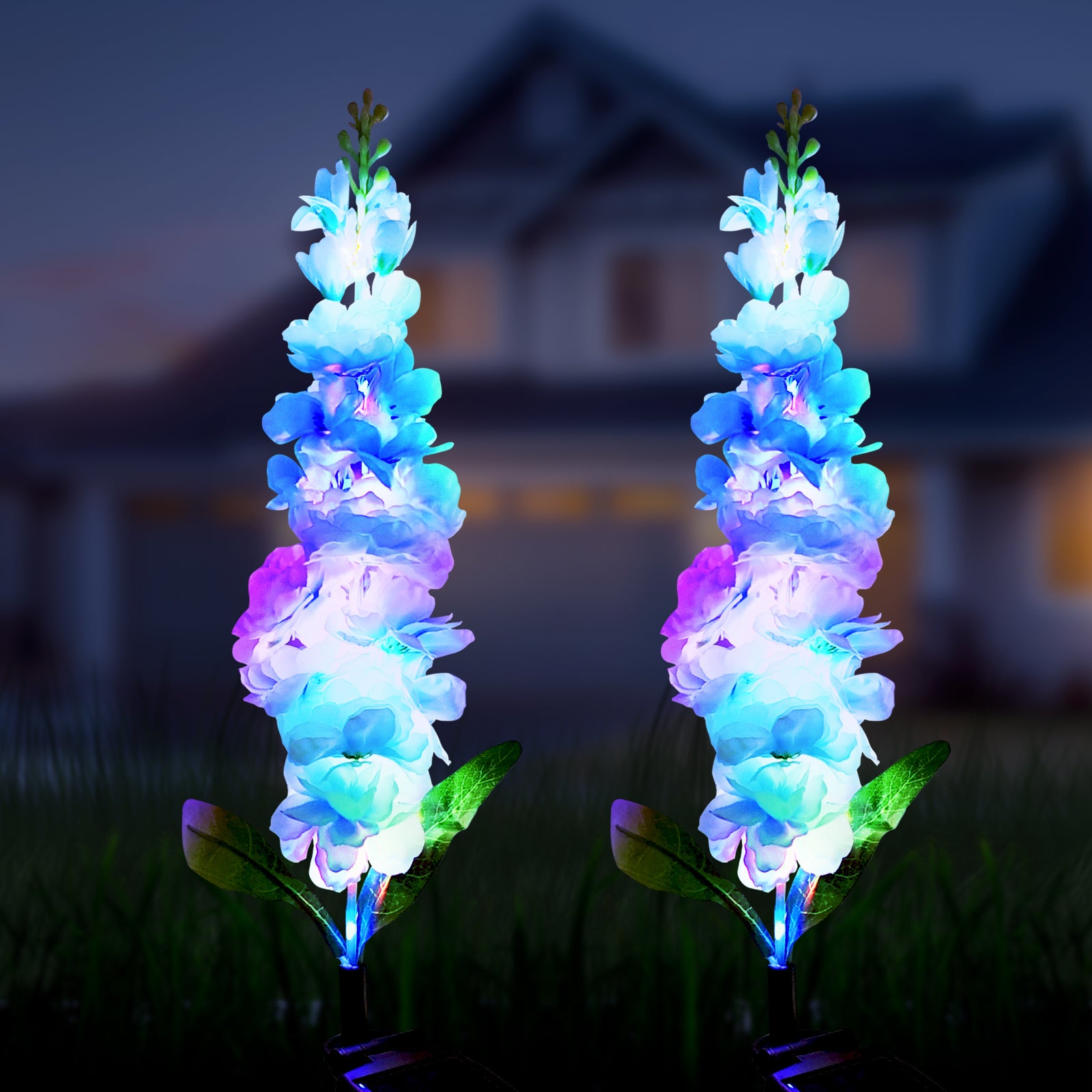 A set of two solar powered integrated LED landscape lights designed to resemble real flowers, illuminating a garden at night.
