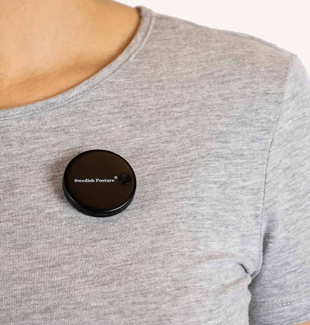 Vibe Posture Digital Sensor attached to a shirt, showcasing its compact design and magnetic closure.