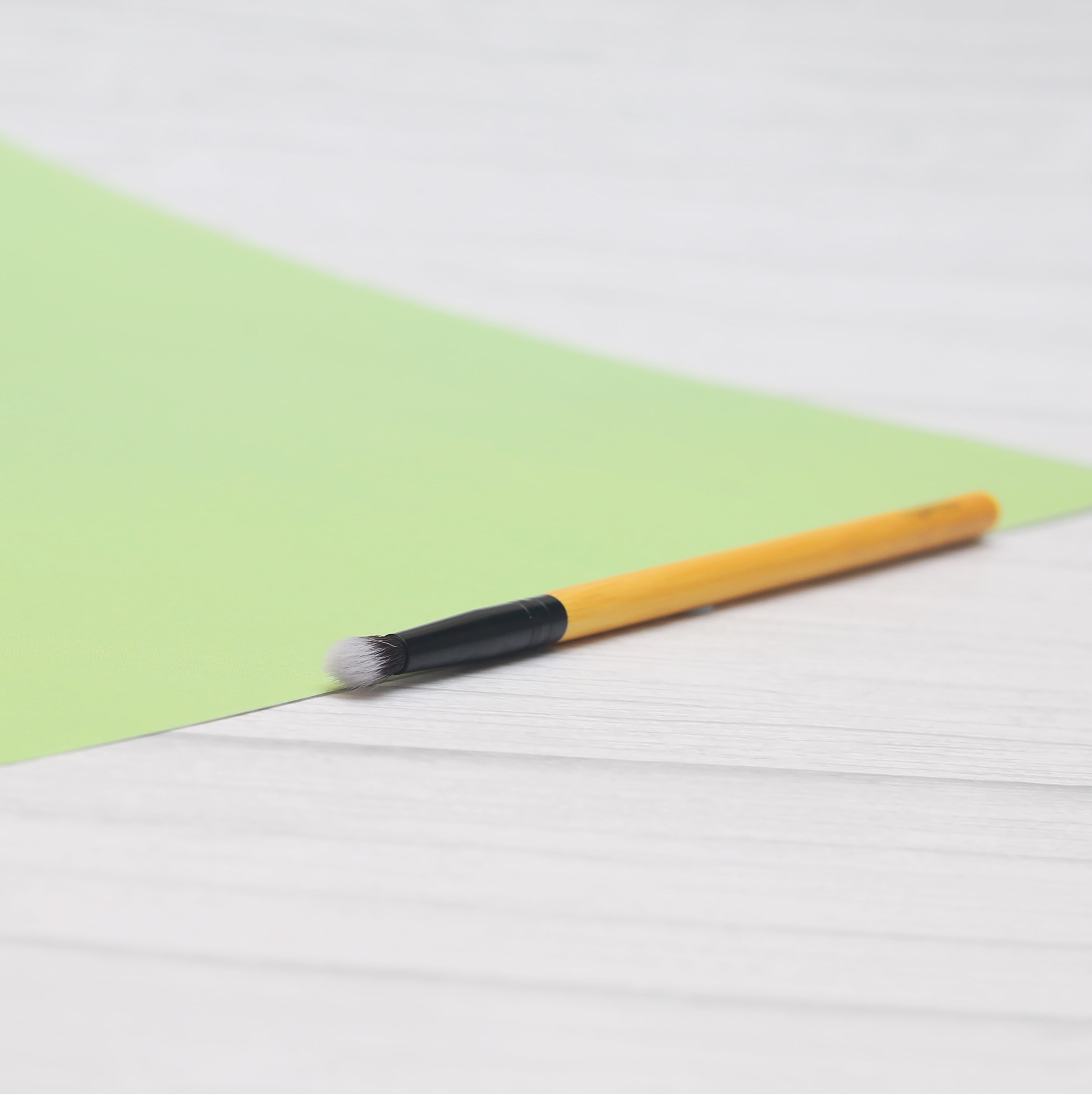 A close-up of a vegan detailing brush with a bamboo handle and soft synthetic bristles, ideal for precise makeup application.