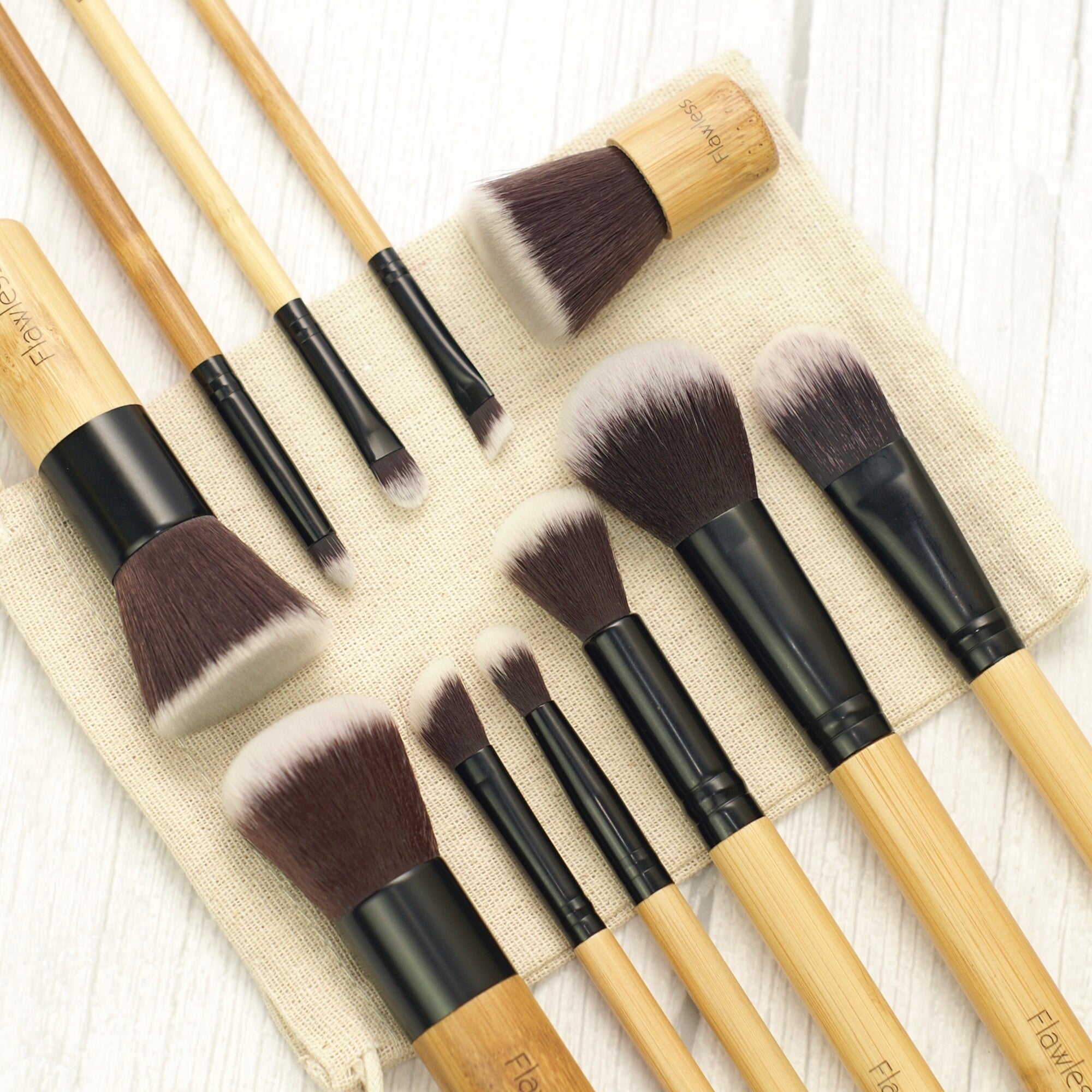 Sustainable 11-Piece Makeup Brush Set displayed with organic cotton bag, showcasing various brushes for flawless makeup application.