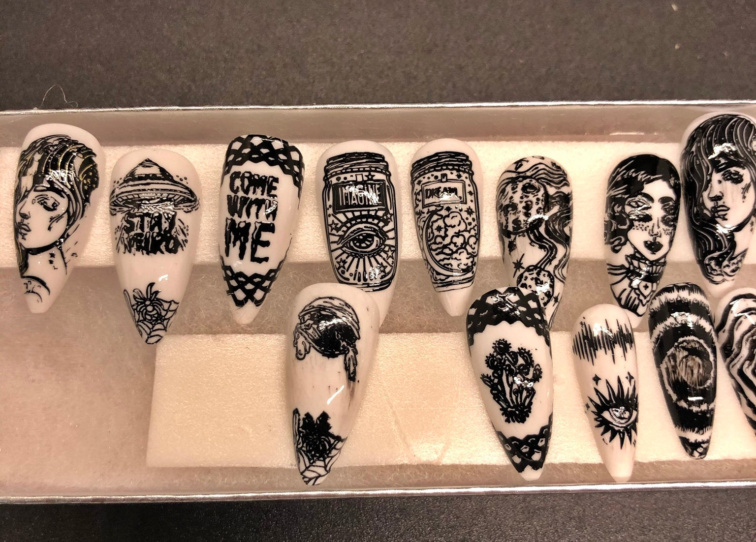 A set of 24 alien-themed false nails with various designs, perfect for press-on application and includes glue stickers.