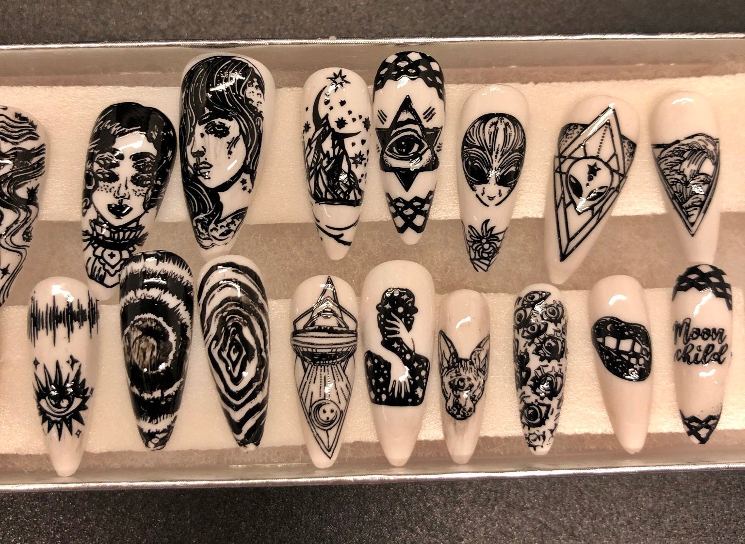 A set of 24 alien-themed false nails with various designs, perfect for press-on application and includes glue stickers.