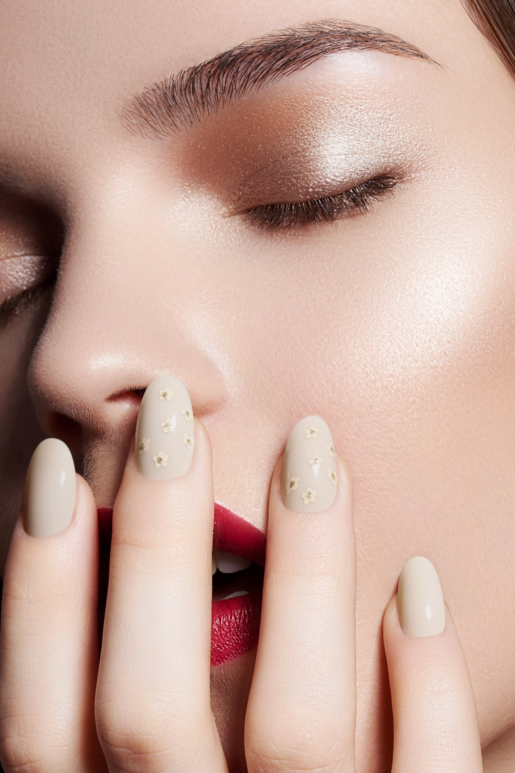 Cotton Daisy press-on nails featuring an ivory base with delicate daisy patterns and gold glitter accents, showcasing elegance and sophistication.