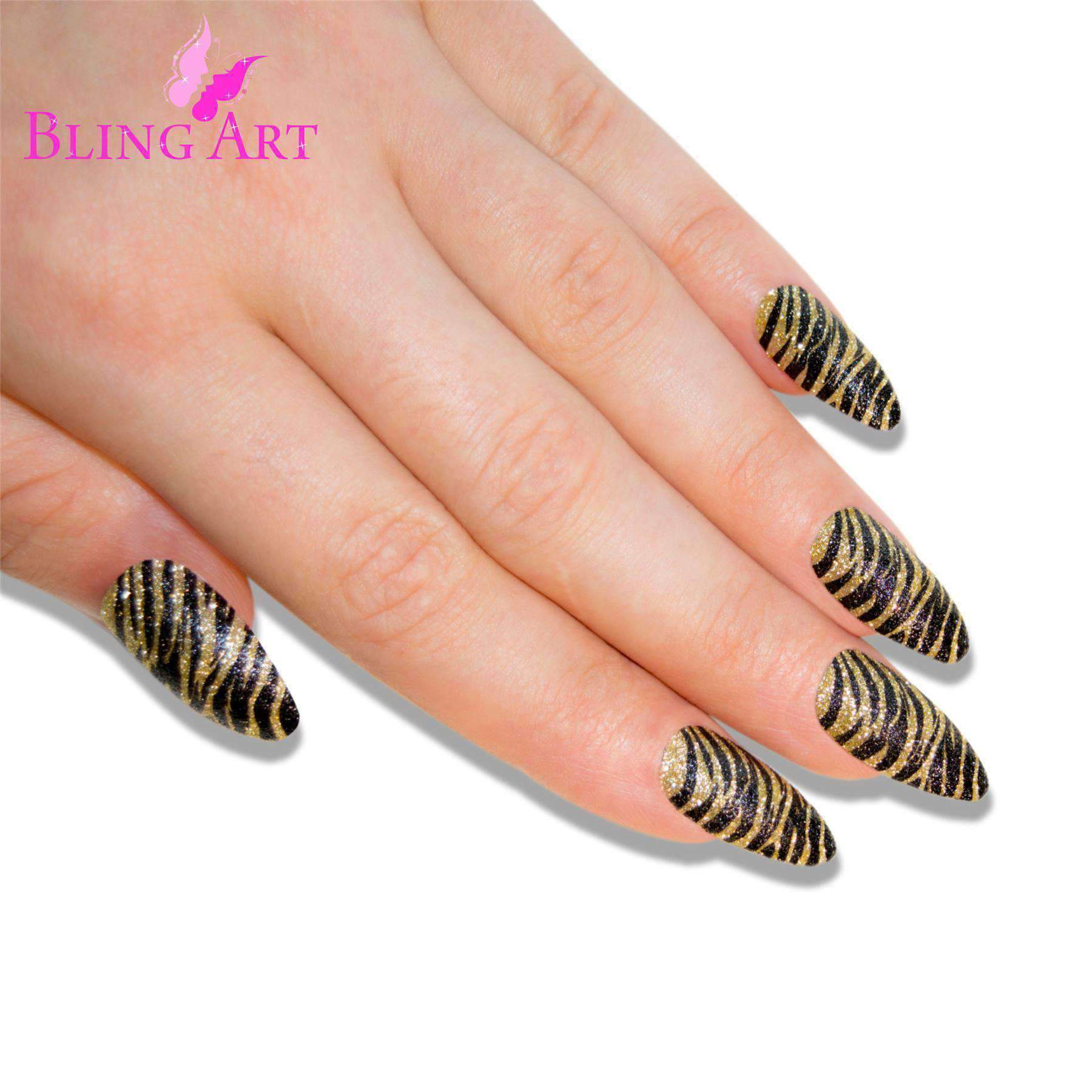A set of 24 long almond stiletto false nails in black and gold glitter design, accompanied by a glue stick, nail file, and cuticle stick.
