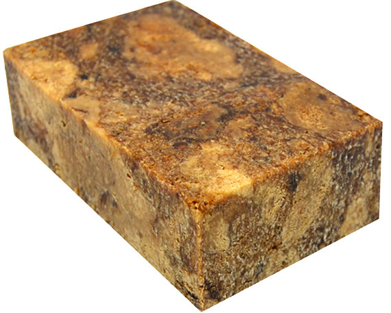 A bar of African Black Soap made from natural ingredients, showcasing its rich, dark color and rustic texture, symbolizing traditional West African craftsmanship.