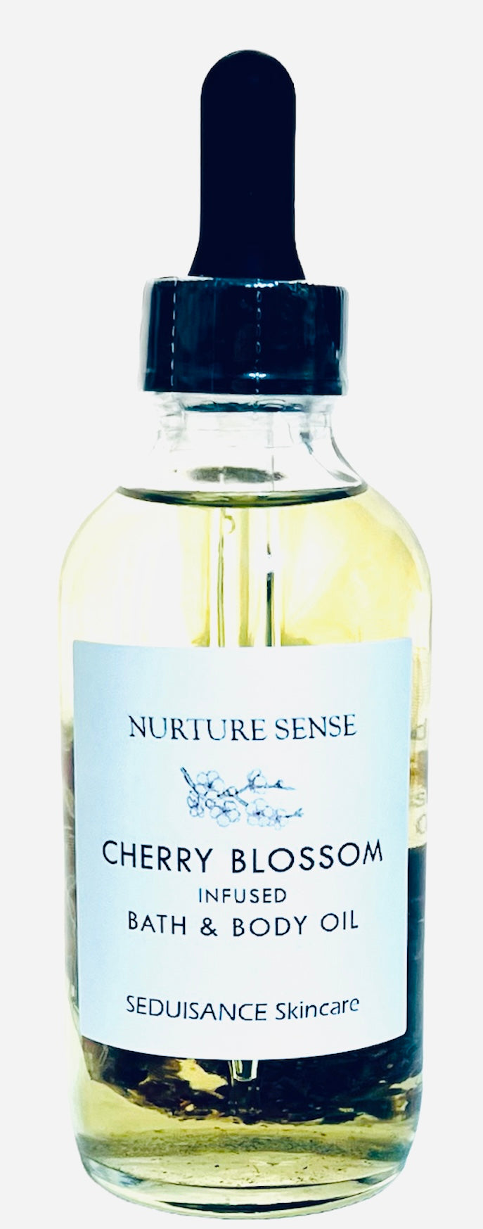 A bottle of Cherry Blossom Infused Bath & Body Oil with cherry blossom flower buds, showcasing its natural ingredients and elegant packaging.