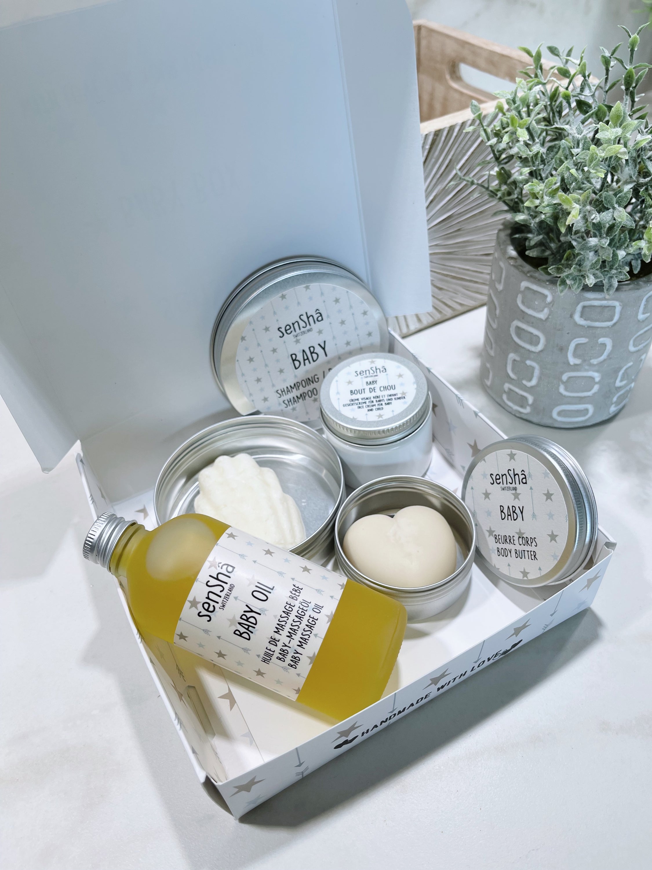 Coffret cadeau Baby Box avec produits pour bébés, incluant shampoing solide, huile, crème et beurre, présenté dans une boîte élégante.