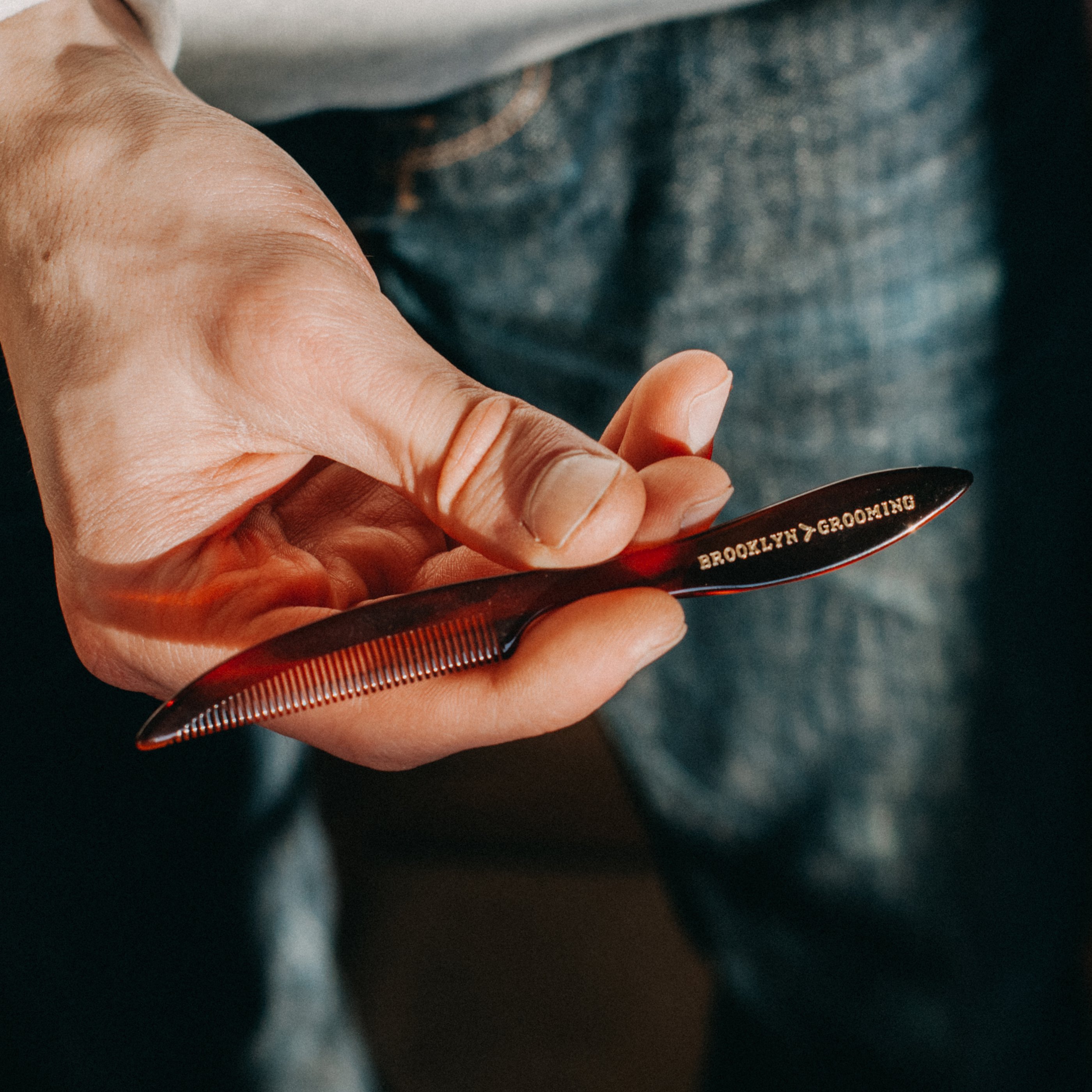 Men's Handmade Mustache and Beard Comb with custom engraving and rounded tips, displayed in a hand stamped muslin bag.