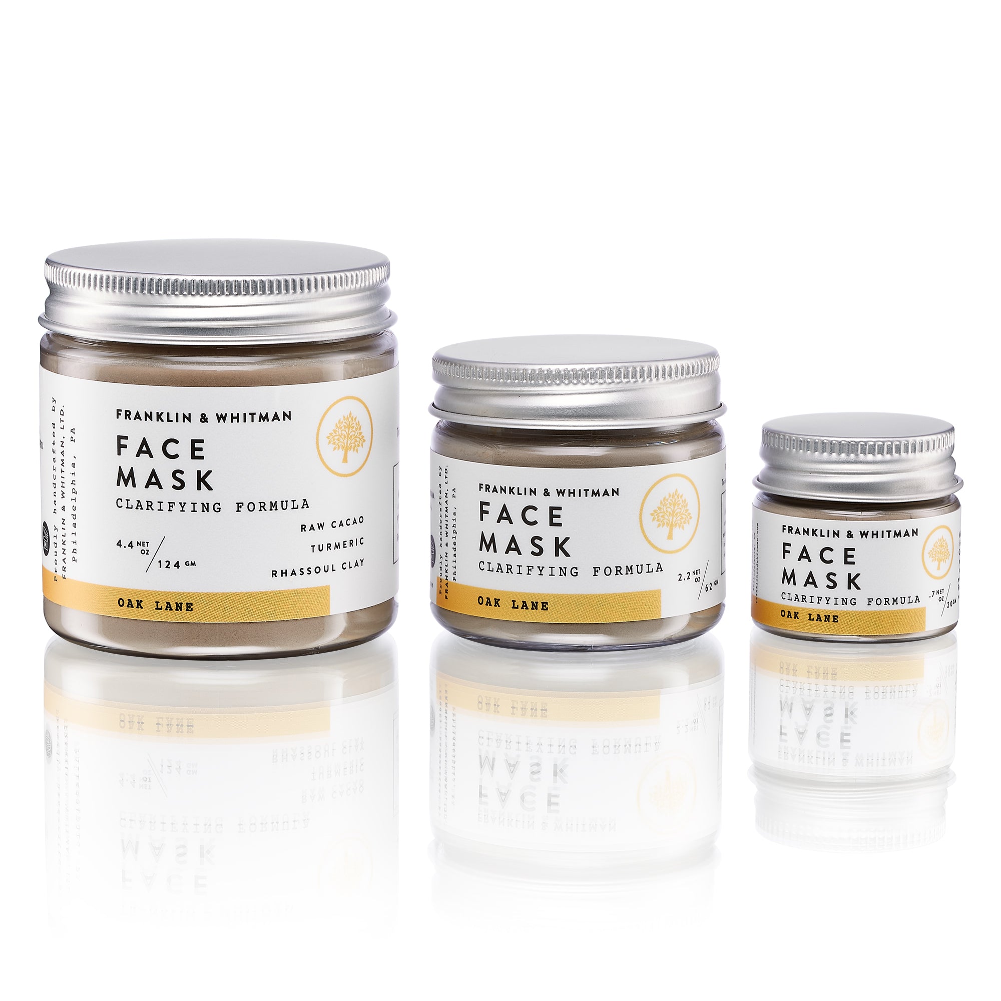 Oak Lane Clay Mask in a jar with a wooden spoon, showcasing its rich brown powder texture, surrounded by natural ingredients like cacao and turmeric.