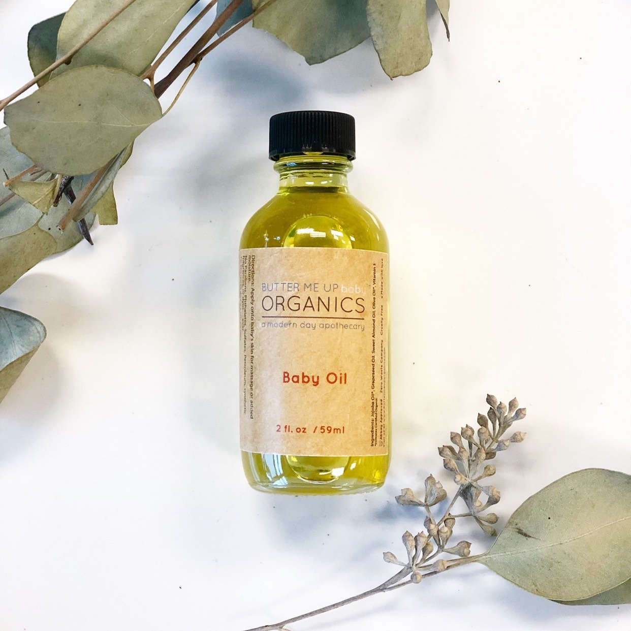 A 2 oz. glass bottle of Organic Gentle Baby Oil with a metal screw top, showcasing its eco-friendly packaging and natural ingredients.