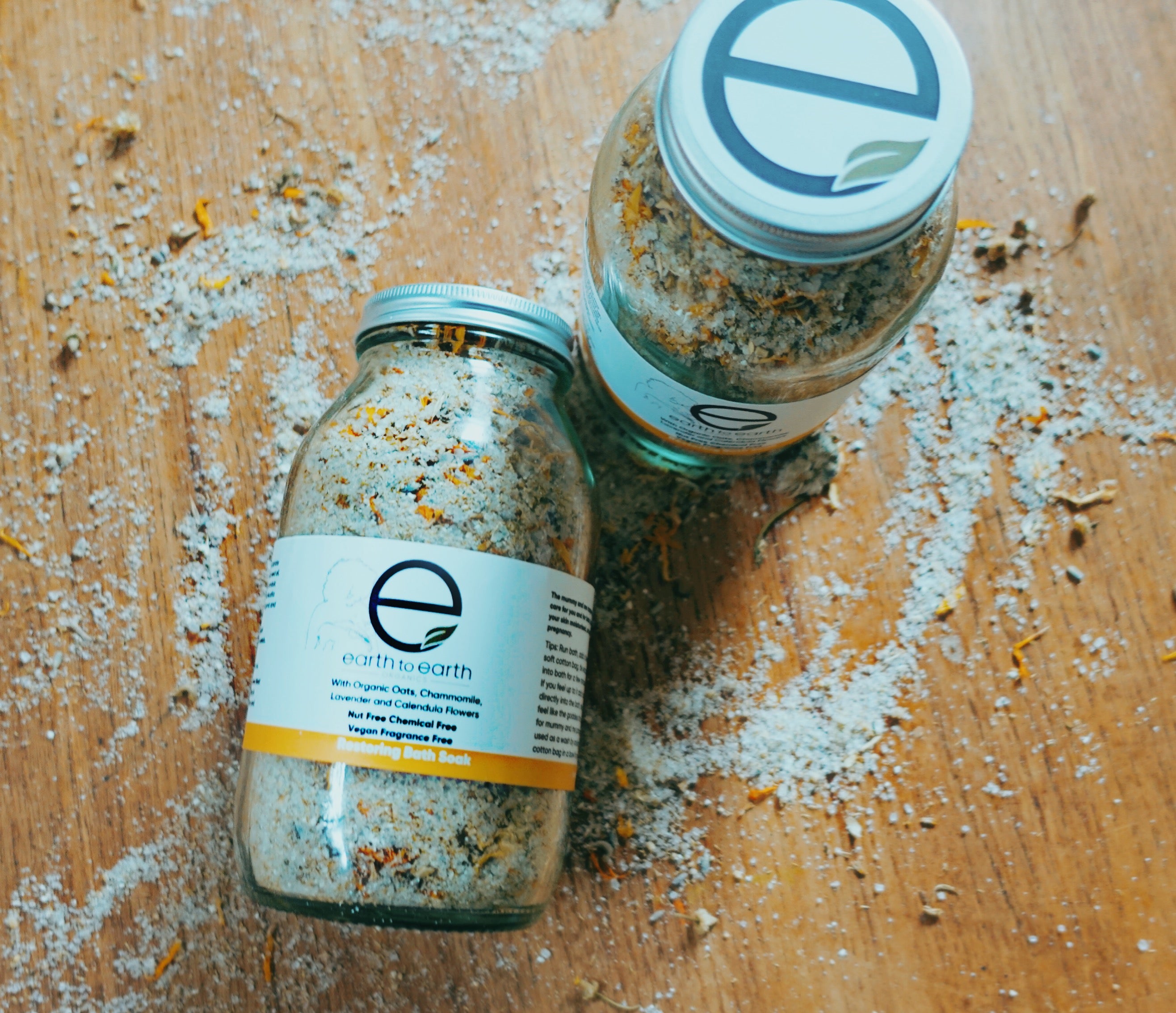 A soothing bath soak featuring chamomile flowers and organic oats in a clear bag, surrounded by calming lavender and calendula petals.