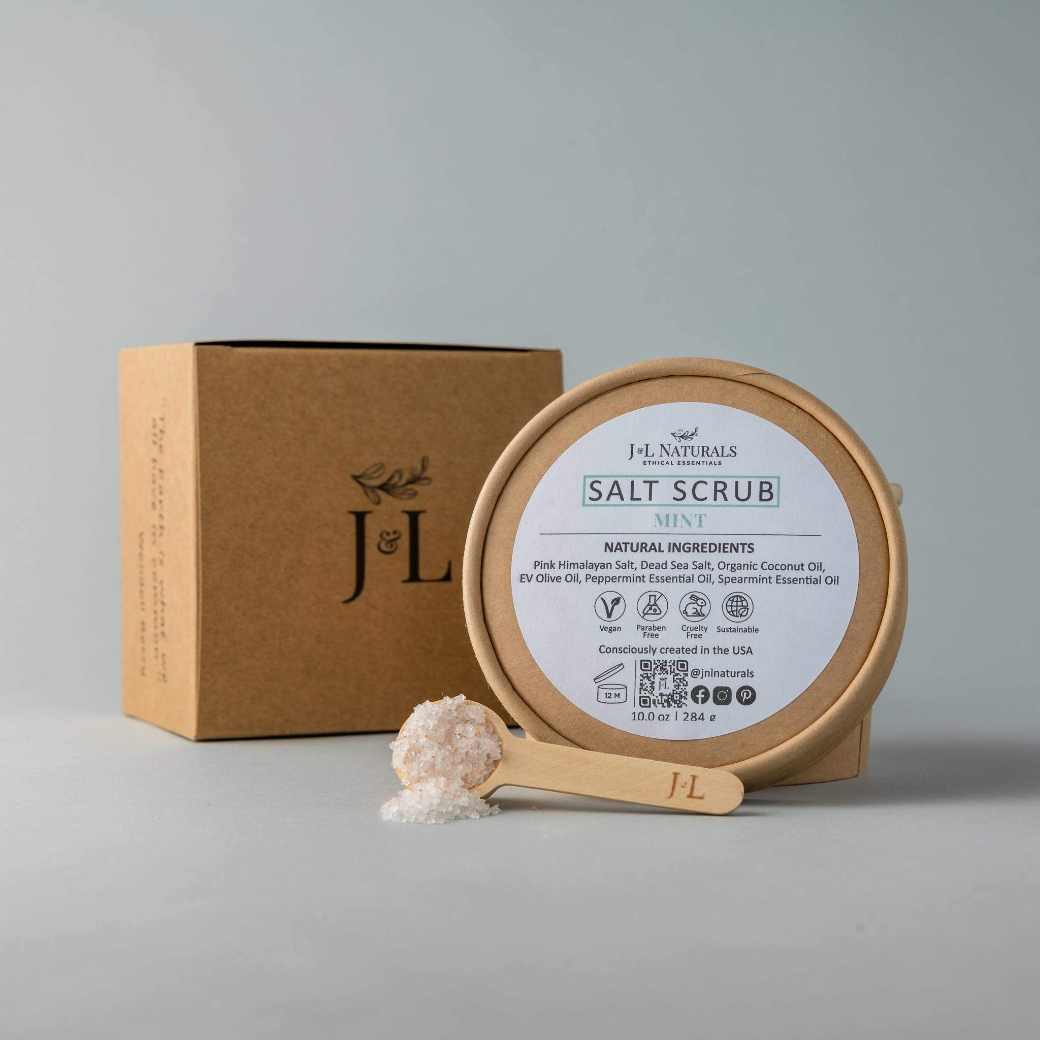 A jar of Salt Scrub featuring pink Himalayan salt and dead sea salt, with a scoop beside it, showcasing its natural exfoliating ingredients.