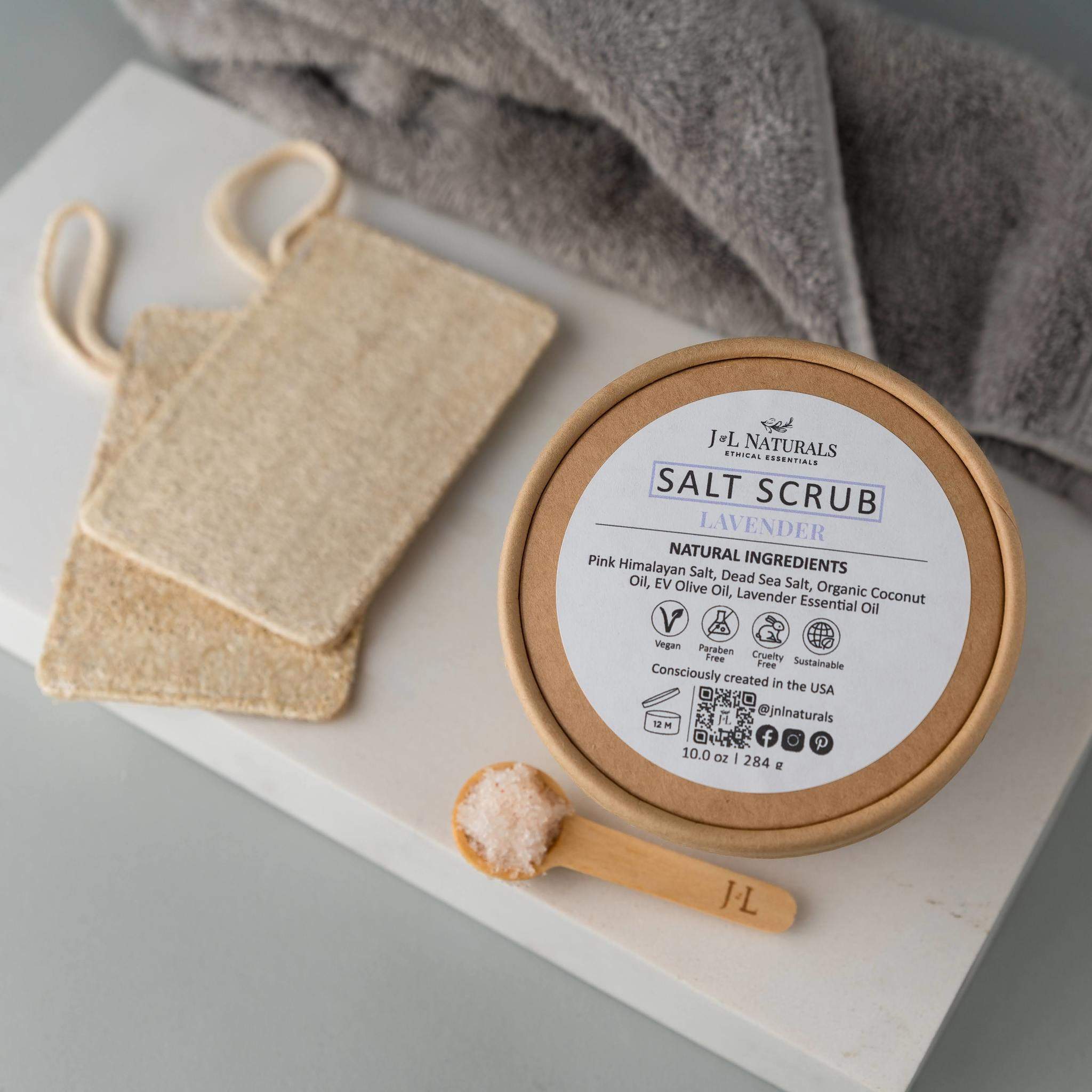 A jar of Salt Scrub featuring pink Himalayan salt and dead sea salt, with a scoop beside it, showcasing its natural exfoliating ingredients.