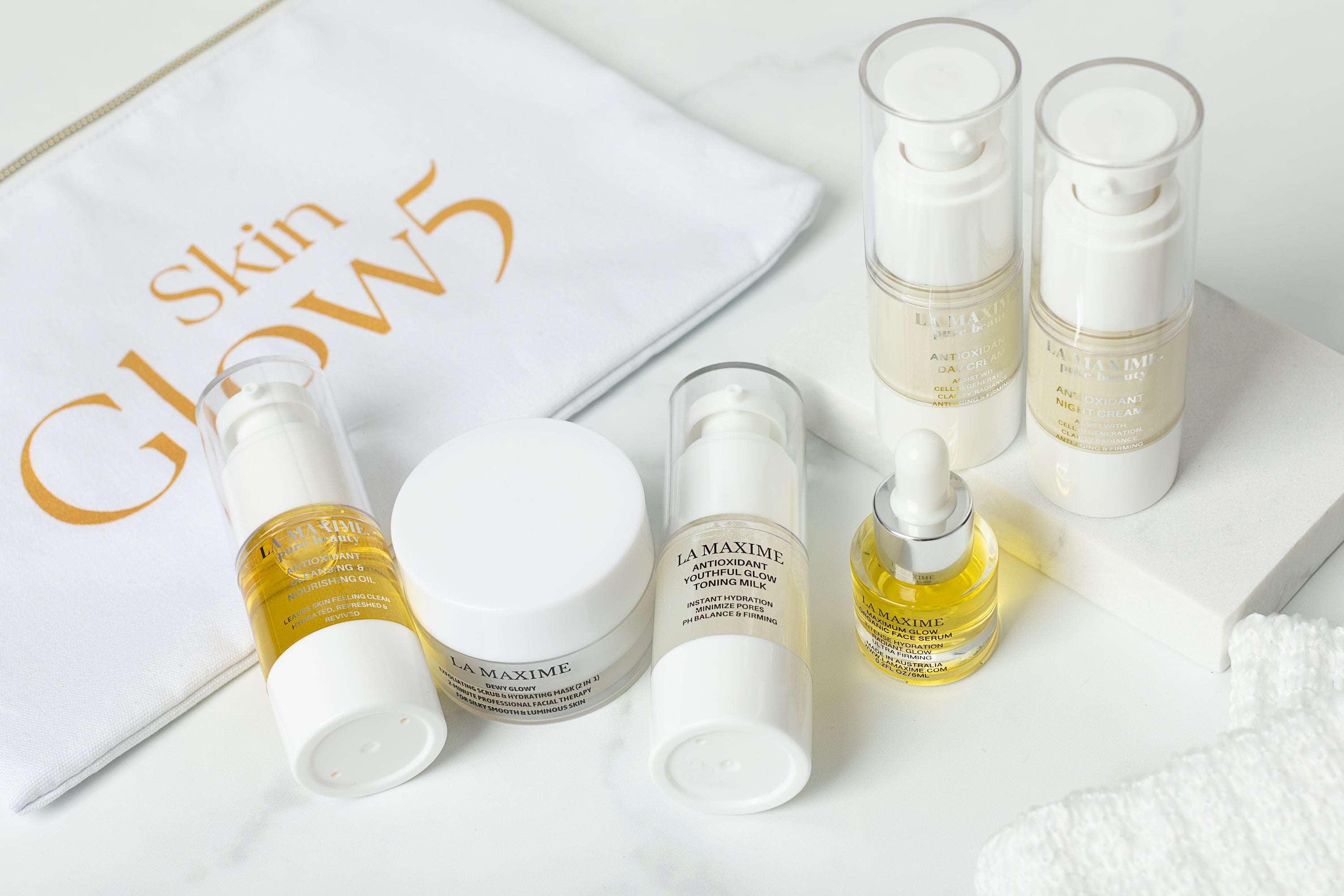 SKINGLOW5 Anti-aging Skincare Set for Travel featuring cleansing oil, scrub, serum, and moisturizers in a stylish beauty pouch.