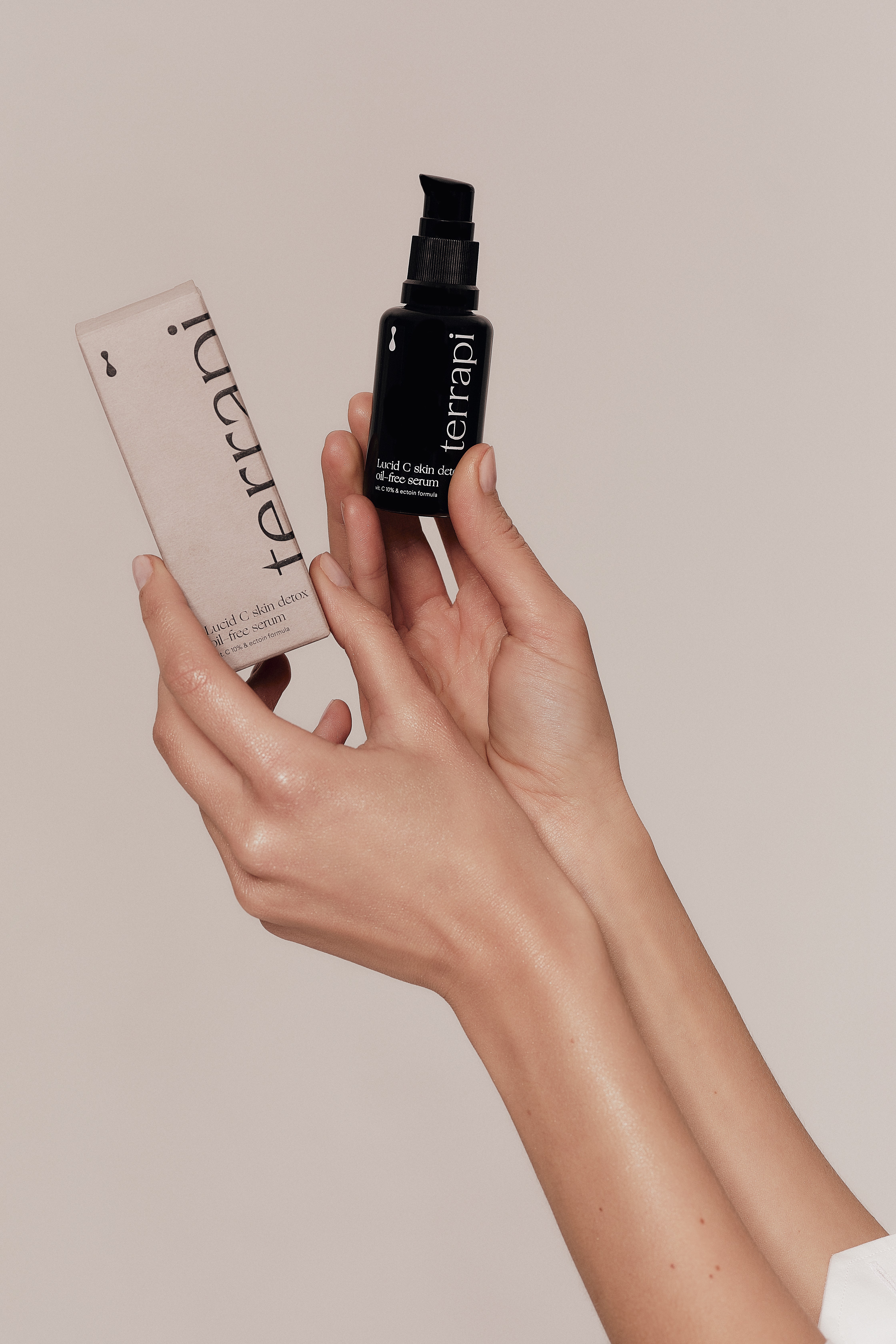 Hands holding skincare serum bottle.