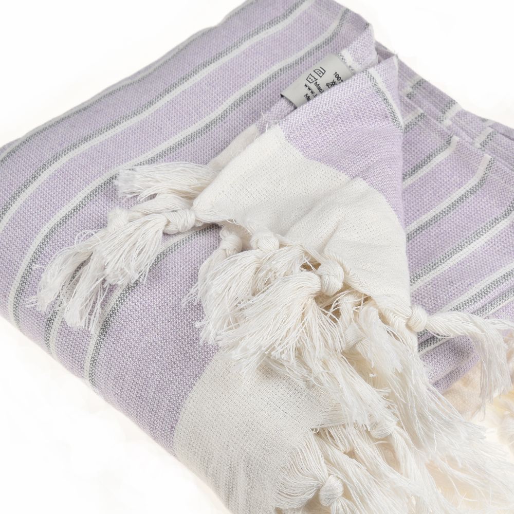 Eftelia Beach Towel displayed on a sandy beach, showcasing its vibrant colors and traditional woven design, perfect for summer outings.