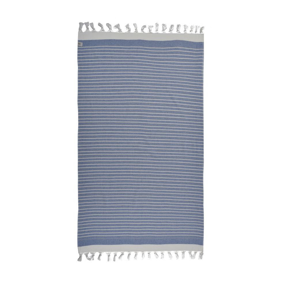 Eftelia Beach Towel displayed on a sandy beach, showcasing its vibrant colors and traditional woven design, perfect for summer outings.