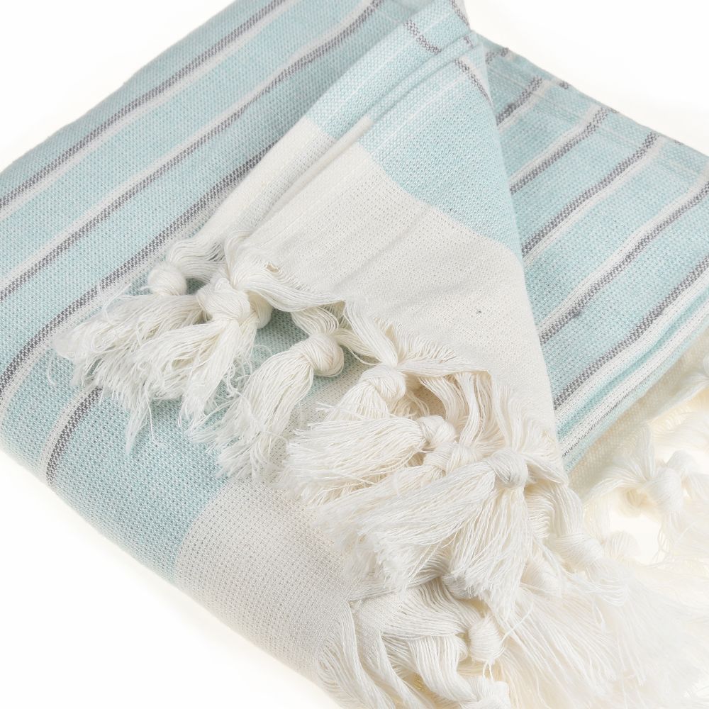 Eftelia Beach Towel displayed on a sandy beach, showcasing its vibrant colors and traditional woven design, perfect for summer outings.