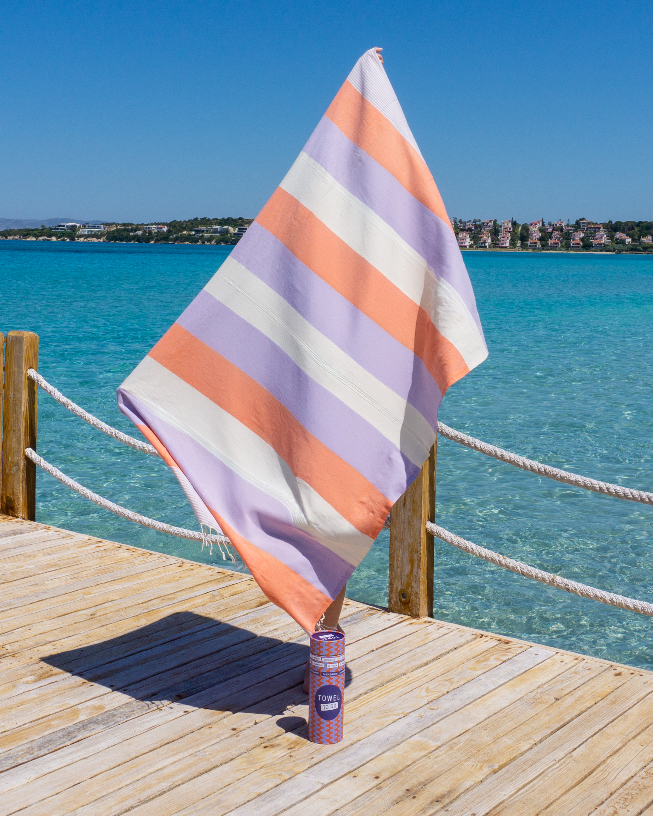 Palermo Beach Towel in vibrant orange and purple stripes, handwoven from 100% cotton, displayed in a recycled gift box.