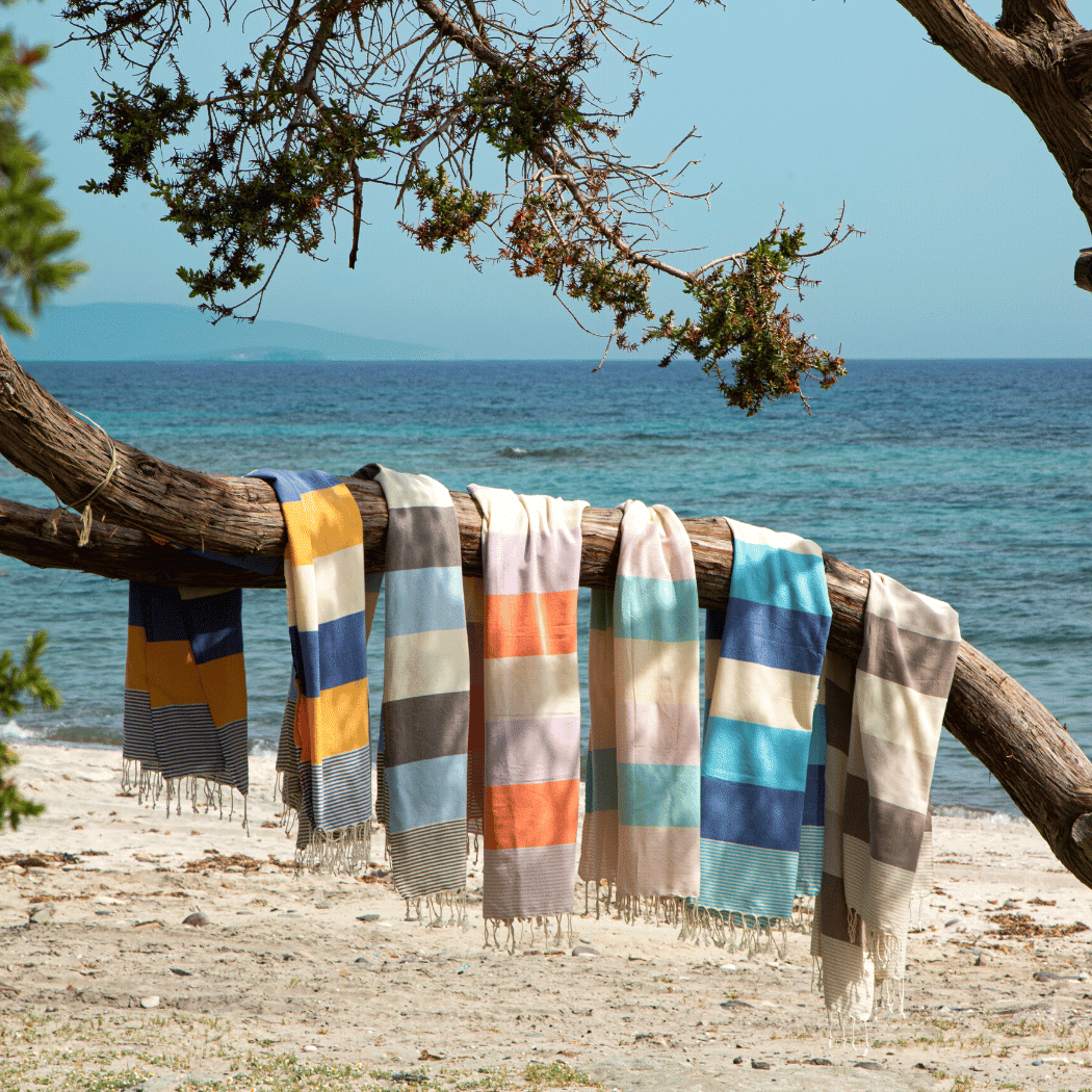 Palermo Beach Towel in vibrant orange and purple stripes, handwoven from 100% cotton, displayed in a recycled gift box.