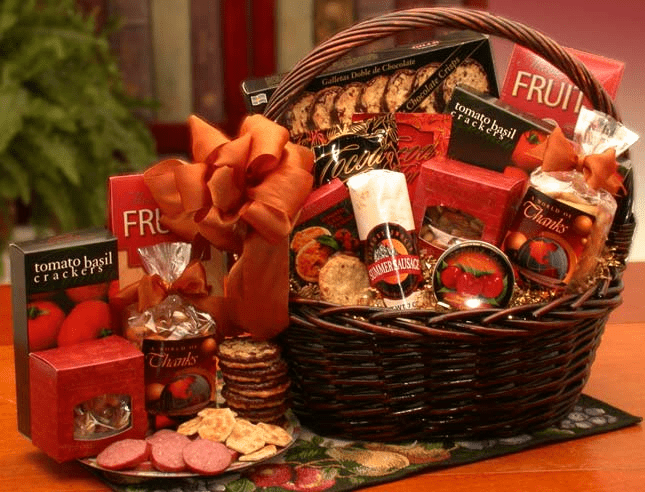 A beautifully arranged gourmet gift basket featuring assorted snacks including crackers, nuts, cheese spread, cookies, and more, presented in a dark stain basket.