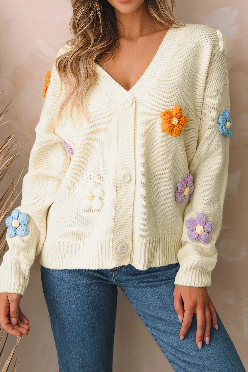 Beige cardigan sweater with colorful flower embellishments and button-up front, perfect for winter fashion.