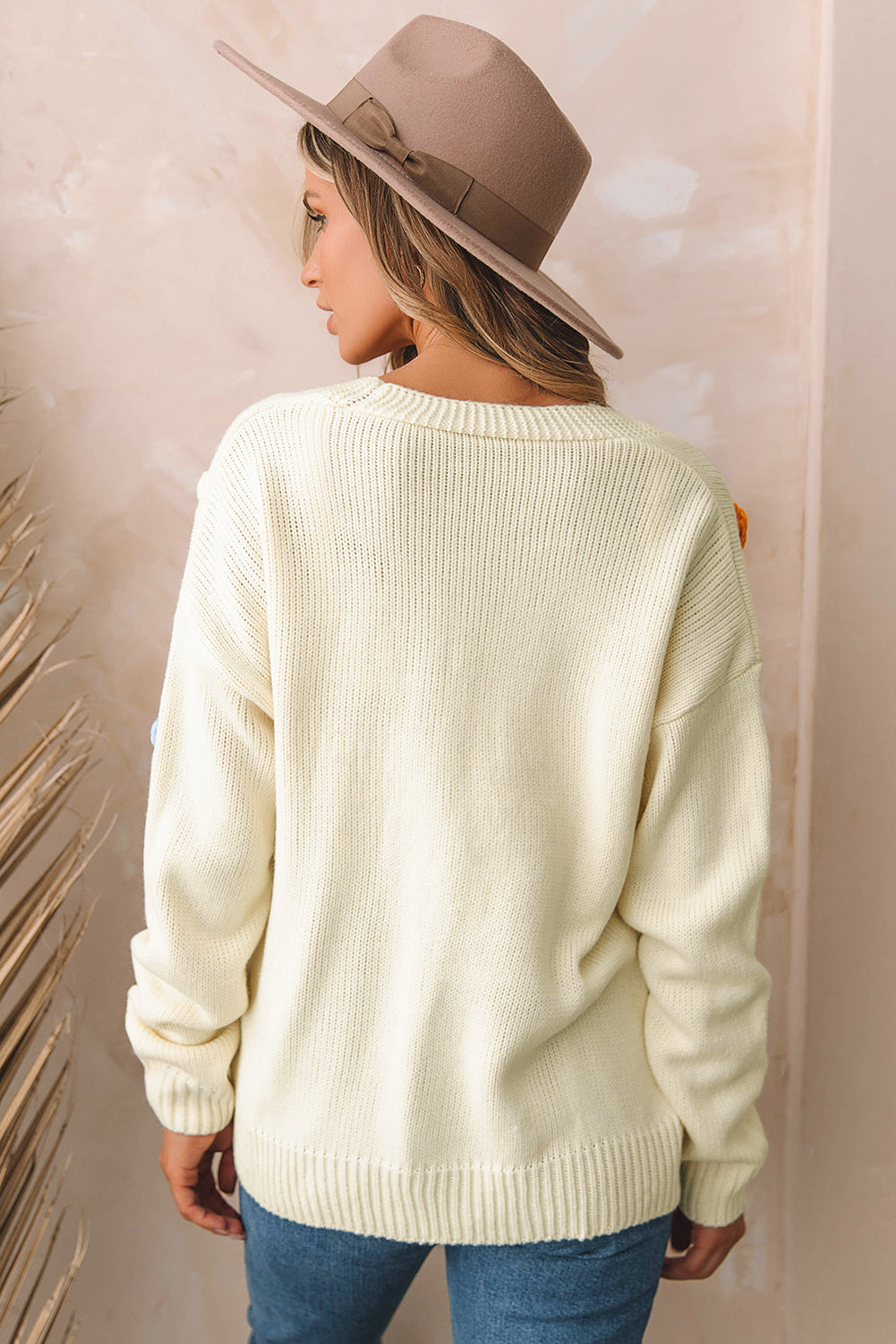 Beige cardigan sweater with colorful flower embellishments and button-up front, perfect for winter fashion.