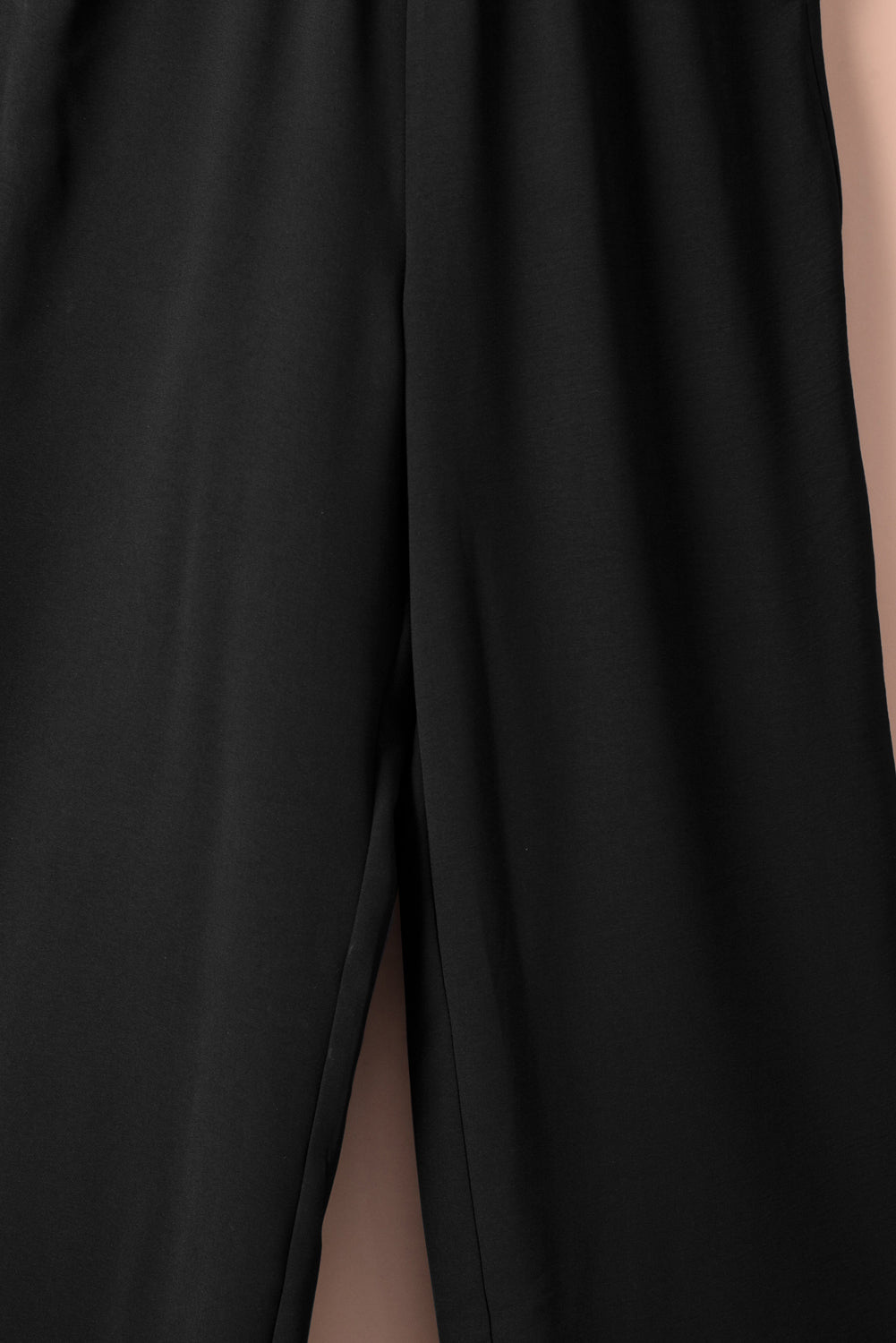 A stylish black jumpsuit featuring flutter sleeves, a smocked bodice, and wide leg bottoms, perfect for any occasion.